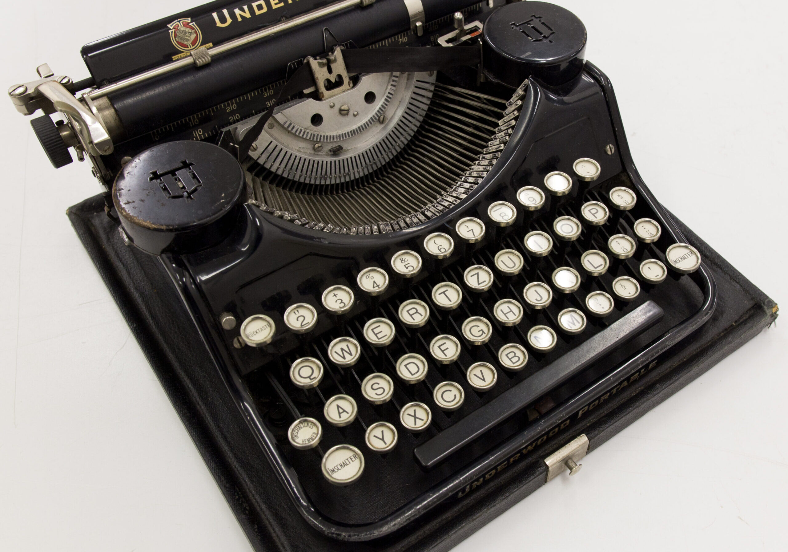 Reise-Schreibmaschine
Underwood Portable
Indetifikations-Nr.: N (9 A) 105/2014
Datierung: 1930-1936
Herstellungsort: Bridgeport, Connecticut, USA
Körperschaft: Underwood Elliott Fisher Company, USA, Hersteller
Höhe x Breite x Tiefe: 15 x 32 x 32 cm mit Deckel
Höhe x Breite x Tiefe: 14 x 30 x 30 cm ohne Deckel
Ausgabe: Holz, Metall
Beschreibung: Schwarze Reise-Schreibmaschine der Firma Underwood Elliott Fisher Company mit schwarzem Deckel. Die Schreibmaschine ist auf der Rückseite beschriftet „Underwood Typewriter Company/ Protected by United States and foreign patents/ Manufactured in Bridgeport, Conn., USA/ Product of Underwood Elliott Fisher Company“. Schreibmaschine mit Serien-Nr.: 520468 und Garantieschein auf der Innenseite des Deckels.